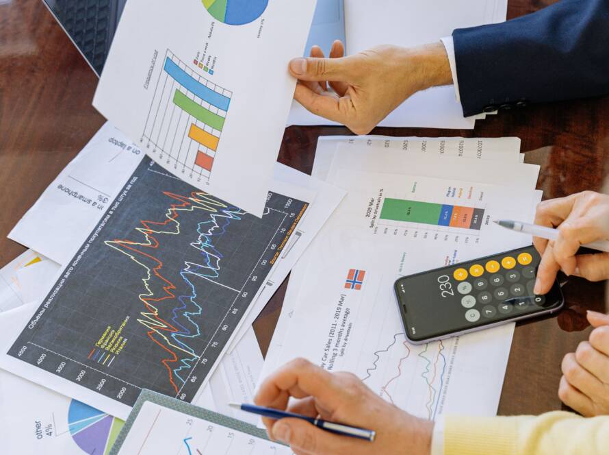 Hands reviewing printed charts and graphs with a calculator on a table