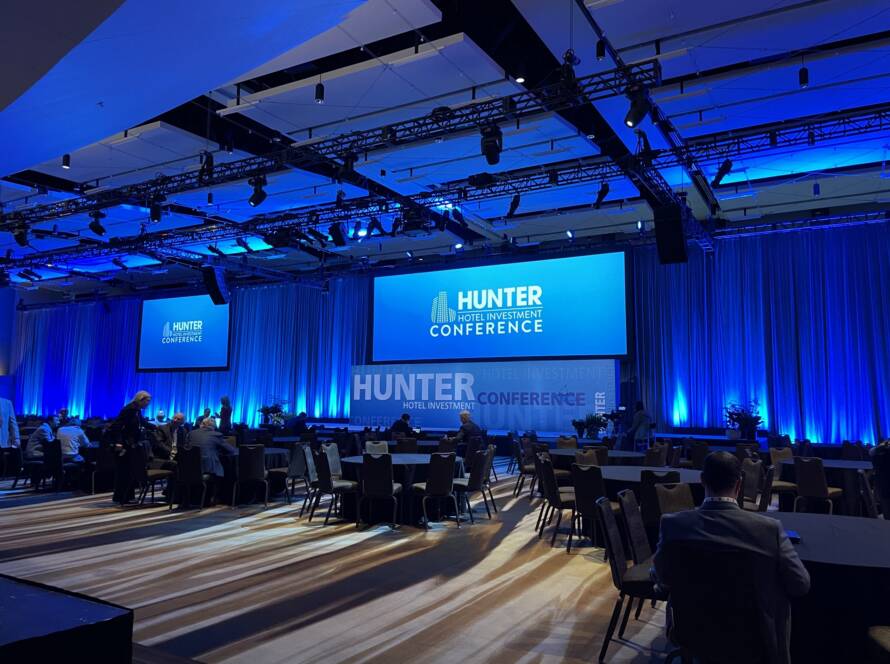 Ballroom set up for the Hunter Hotel Investment Conference with stage screens and blue lighting