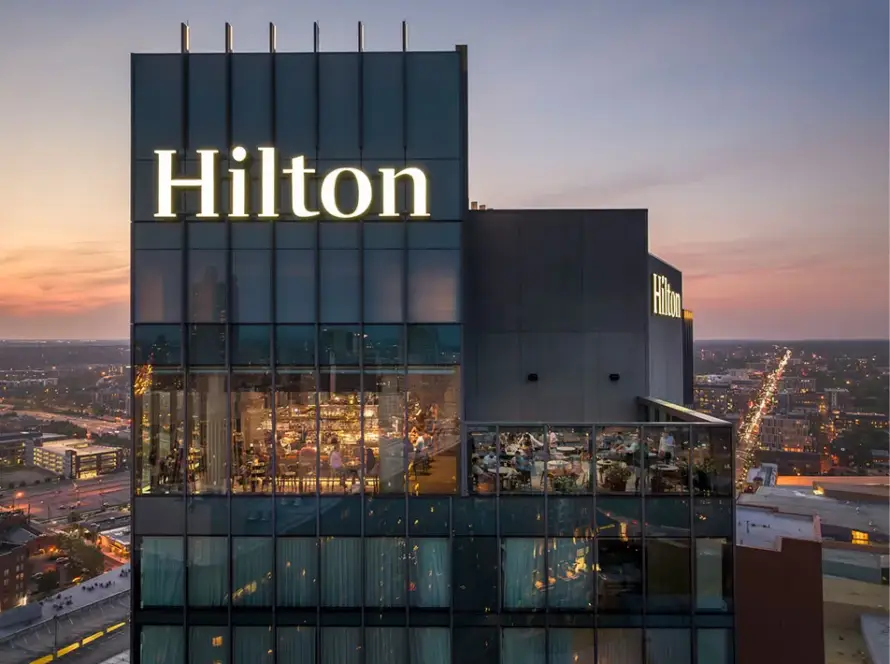 Hilton Columbus Downtown tower at dusk with illuminated Hilton sign and rooftop bar and lounge