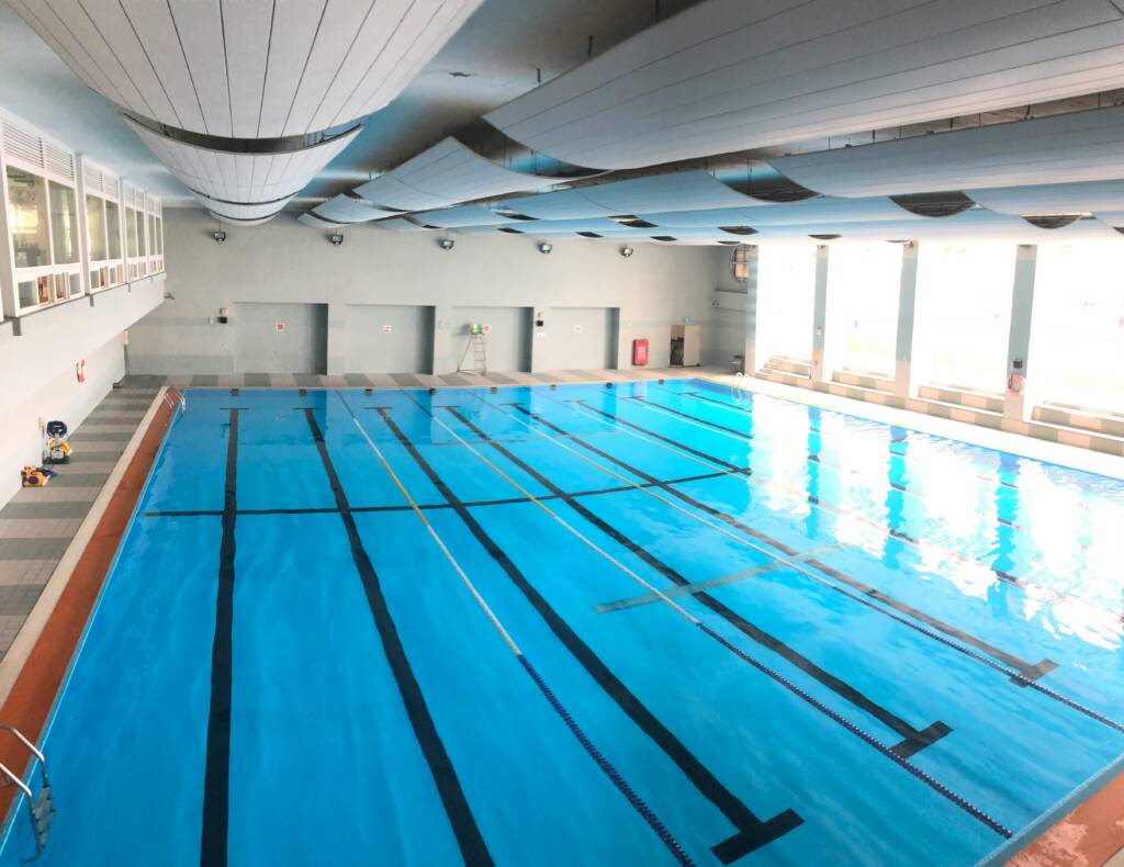 Indoor lap swimming pool with lane lines and a curved acoustic ceiling