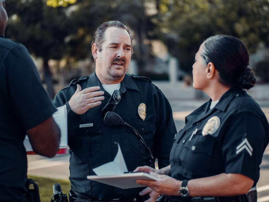 Police officers talking outdoors while one reviews a clipboard