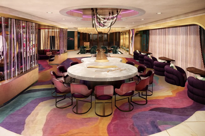 Upscale lounge with a round marble table, plum velvet chairs and a swirling multicolor carpet