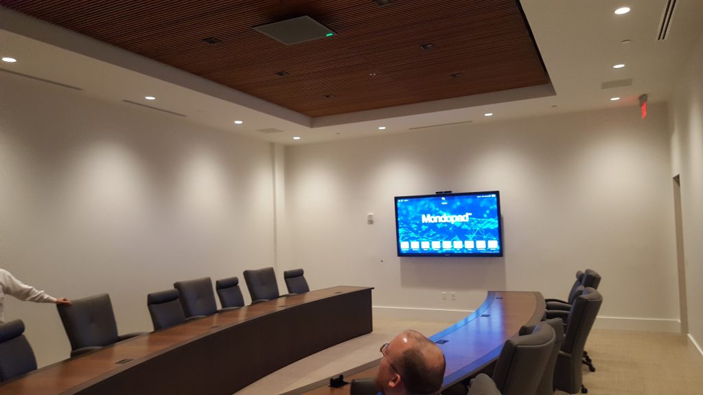 Boardroom with curved conference table and a wall-mounted display