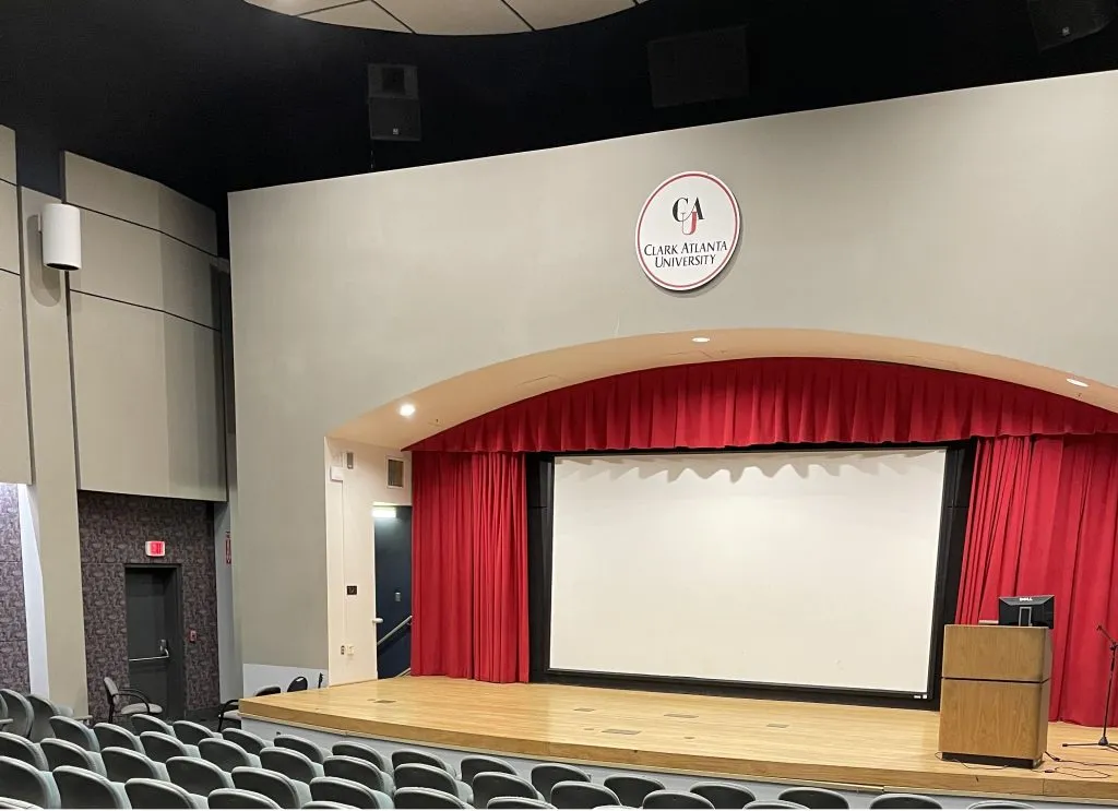 Aldridge Auditorium stage with red curtains, projection screen and Clark Atlanta University seal