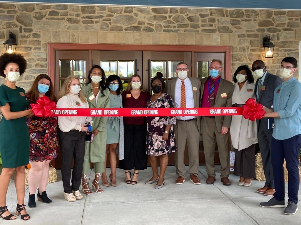 Masked group holding a red "Grand Opening" ribbon at BrightView Columbia