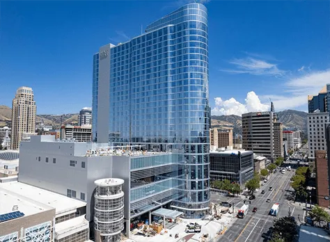 Hyatt Regency glass hotel tower in a downtown setting with mountains behind