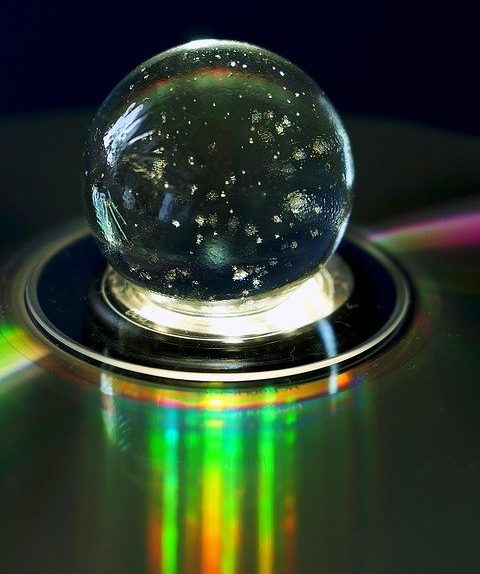 Crystal ball resting on a CD reflecting rainbow light