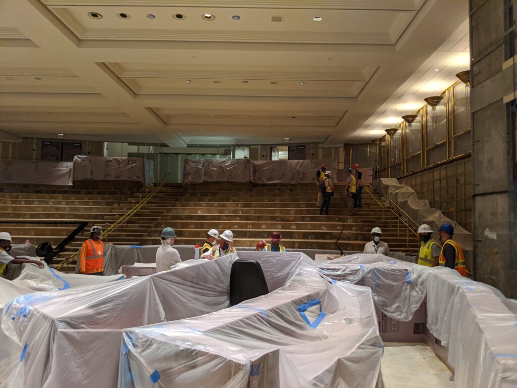 Fulton County Board of Commissioners assembly hall under renovation with covered furniture and workers