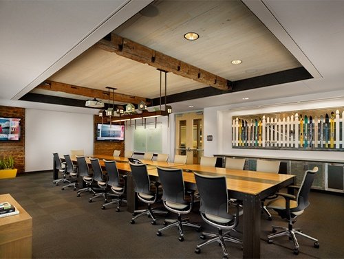 Conference room at HomeAway's Austin office with a long wood table, exposed beams and a wall of skis