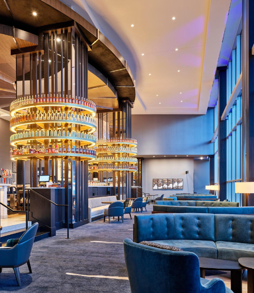 Bar and lounge at Loews Kansas City with a tiered circular liquor display and blue seating