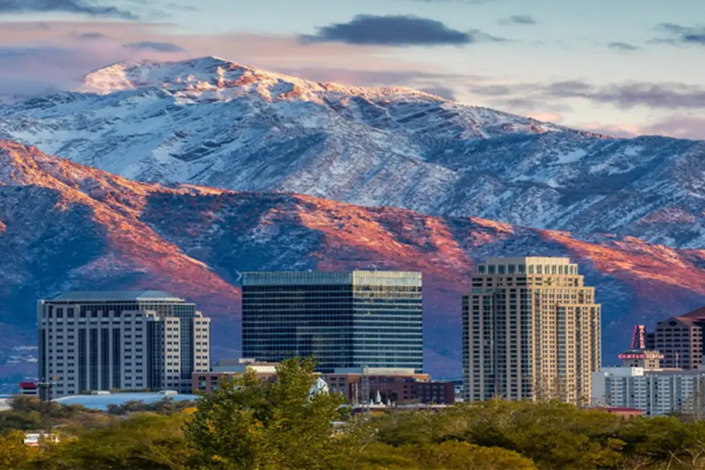 City skyline in front of snow-capped mountains at sunset