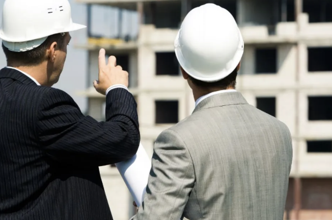 Two men in hard hats looking at a building under construction