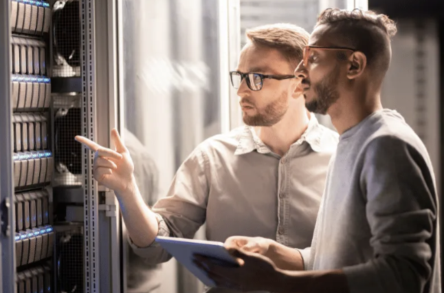 Two IT professionals with a tablet inspecting servers in a data center