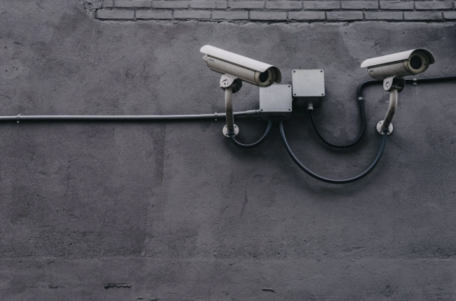 Two security cameras mounted on a gray concrete wall