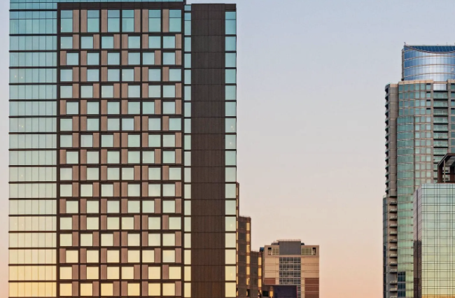 Modern high-rise tower with a grid facade against a dusk sky