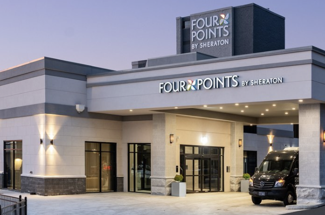 Four Points by Sheraton hotel entrance with illuminated signage and a shuttle van