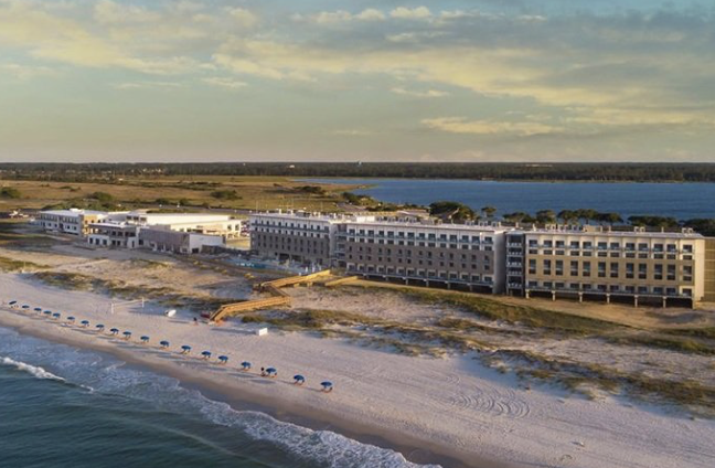 Aerial view of a beachfront resort hotel beside dunes and the ocean