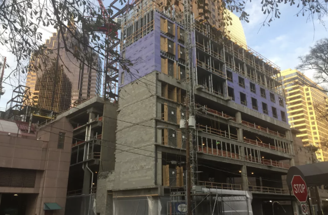 High-rise building under construction with exposed floors between downtown towers