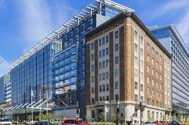 Modern glass building beside a historic brick building on a city street