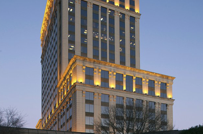 Tall illuminated hotel tower with classical stone detailing at dusk