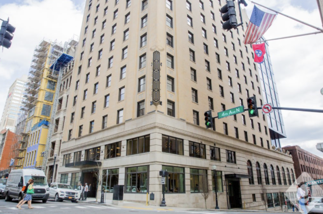 Historic high-rise hotel on a downtown street corner with American and Tennessee flags