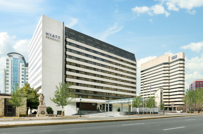 Hyatt Regency hotel tower exterior with neighboring office buildings under a blue sky