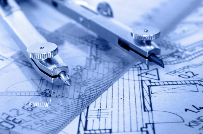 Drafting compass resting on architectural floor plan blueprints