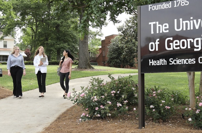 Students walking past The University of Georgia Health Sciences Campus sign