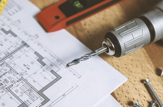 Drill and tape measure resting on architectural floor plans