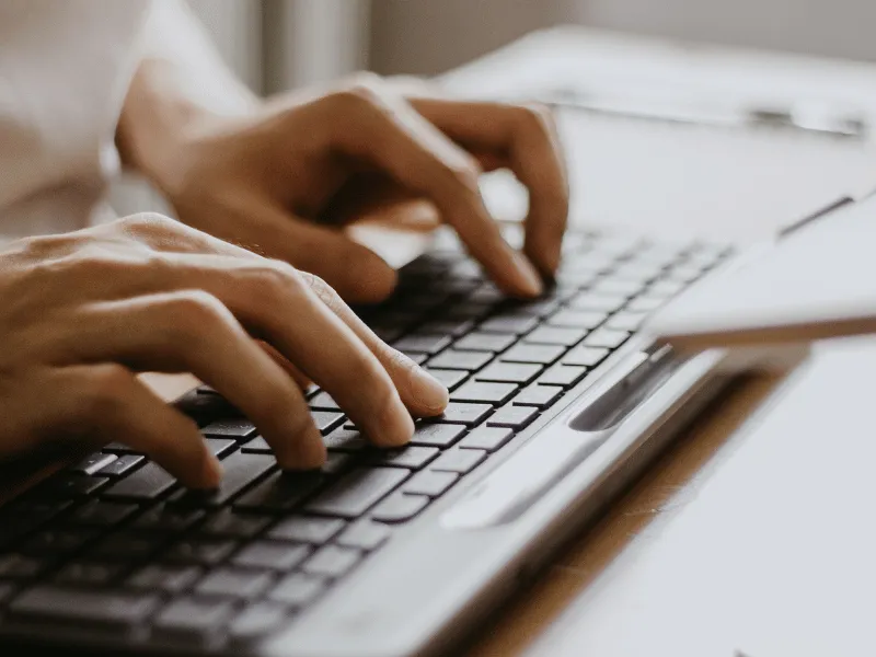 Close-up of hands typing on a laptop keyboard