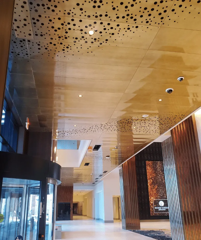 Wind Creek lobby corridor with perforated gold ceiling and wood panels