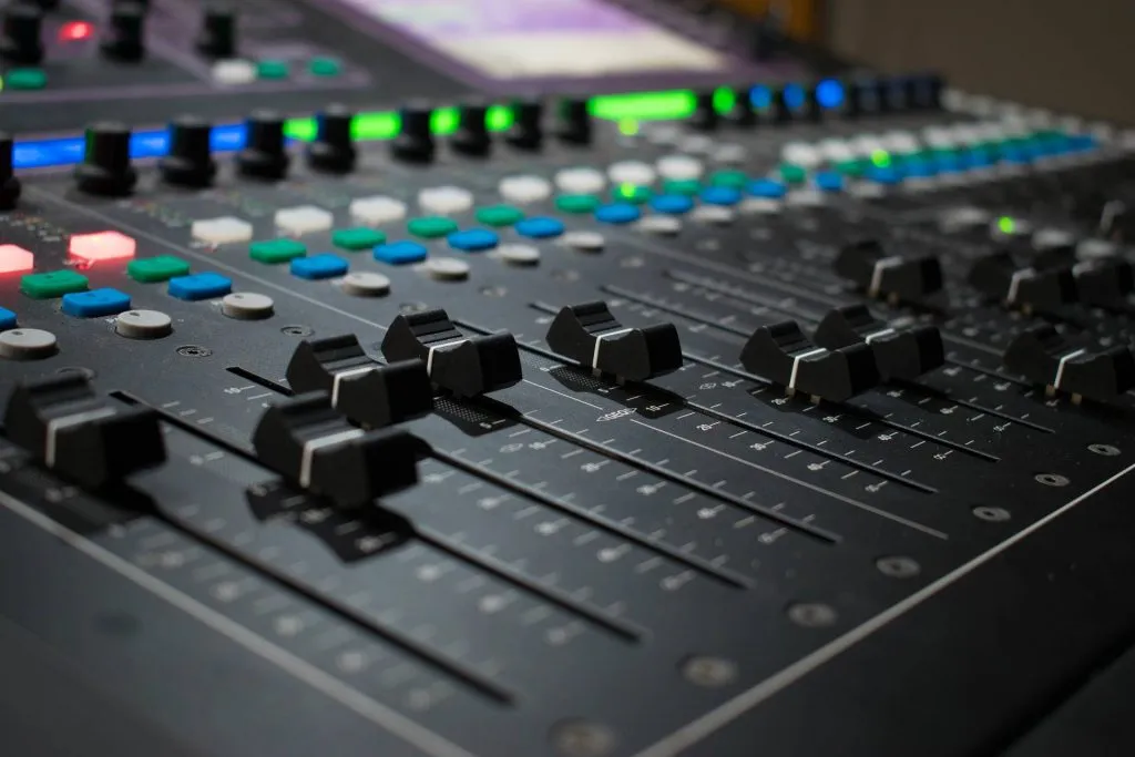 Close-up of an audio mixing console with faders
