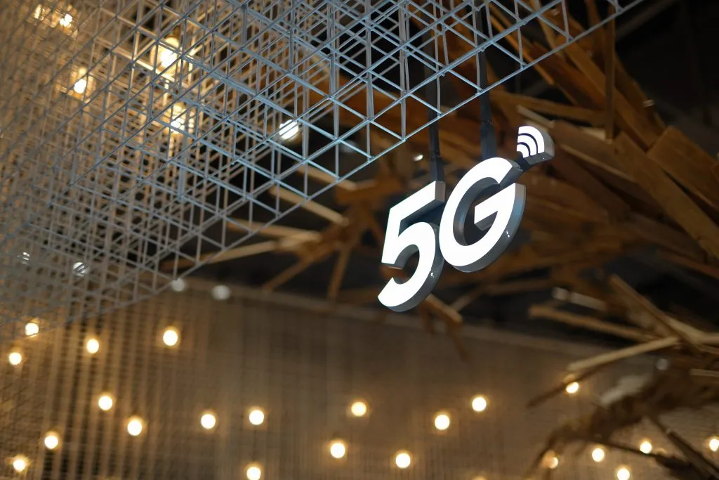 Illuminated 5G sign hanging from a wire mesh ceiling