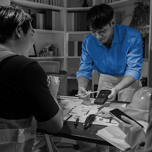 Team reviewing architectural plans with a calculator, with a man in a blue shirt highlighted