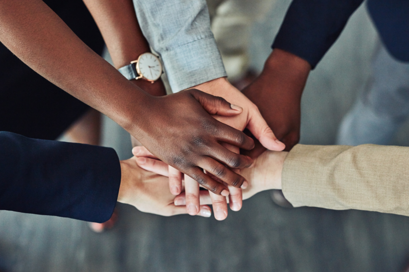 Team members stacking their hands together in a show of unity
