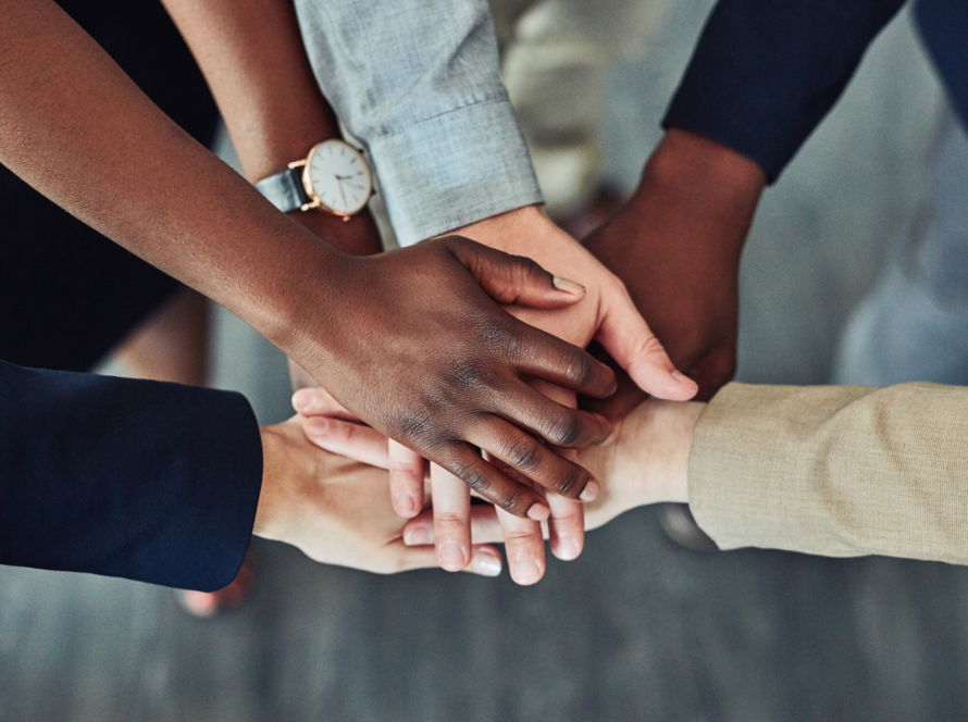 Team members stacking their hands together in a show of unity
