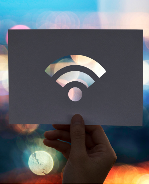 Hand holding a paper card with a Wi-Fi symbol cut out against colorful bokeh lights